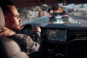 Rear view of handsome unshaved man in fashionable clothes that riding his automobile photo