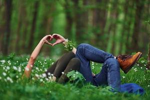 Couple lying down on the grass in forest together at daytime photo