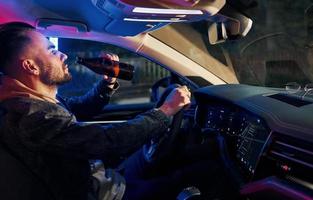 Black and red police lights. Dont drink and drive. Side view of handsome unshaved man in fashionable clothes inside his automobile photo