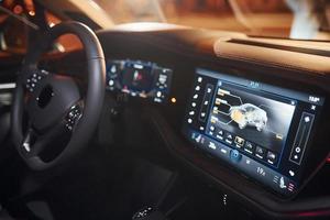 Steering wheel and navigation display. Close up view of front park of new modern black automobile photo