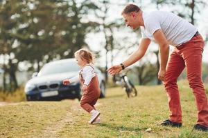 Father in casual clothes have walk and fun with daughter outdoors near forest photo