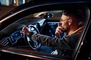 Tired handsome unshaved man in fashionable clothes riding his automobile photo