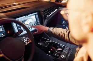Using navigation display. Handsome unshaved man in fashionable clothes riding his automobile photo