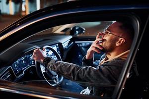 Tired handsome unshaved man in fashionable clothes riding his automobile photo