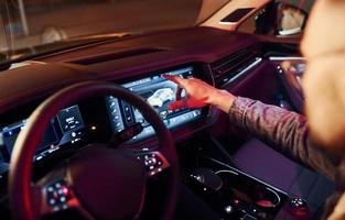Using navigation display. Handsome unshaved man in fashionable clothes riding his automobile photo