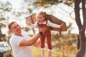 Father with his little daughter have fun outdoors with handmaded wooden wings photo