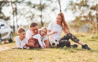 familia feliz pasando el fin de semana juntos al aire libre cerca del bosque. con hija e hijo foto