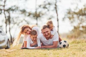 familia feliz pasando el fin de semana juntos al aire libre cerca del bosque. con hija e hijo foto