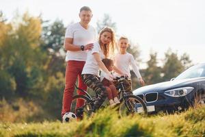 With bikes near the car. Happy family spending weekend together outdoors near the forest. With daughter and son photo