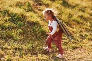 Cute little girl with handmaded wings running outdoors on the field and having fun photo