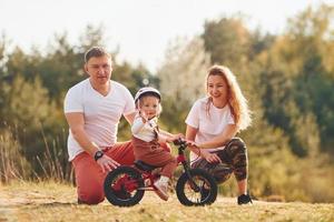 Mother and father teaching daughter how to ride bicycle outdoors photo