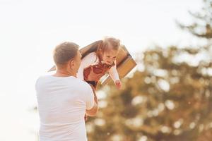 padre con su pequeña hija divertirse al aire libre con alas de madera hechas a mano foto