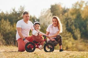 Mother and father teaching daughter how to ride bicycle outdoors photo