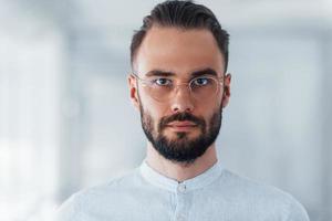 Portrait of young handsome man in formal clothes indoors in the office at daytime photo