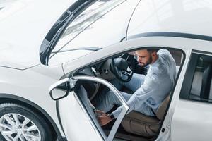 Young handsome man in formal clothes sitting in brand new automobile photo