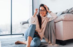 mujer joven y hermosa con ropa informal y gafas sentada sola en casa foto