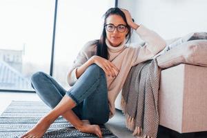 mujer joven y hermosa con ropa informal y gafas sentada sola en casa foto