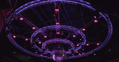 Nachtdisco mit neonblauem violettem Rotlicht, Disco-Spiegelkugel und hellem Flutlicht mit runder Metallrahmen-Leuchtkonstruktion video