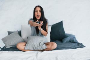 Holding TV remote and watching movie. Young beautiful woman in casual clothes sitting at home alone photo