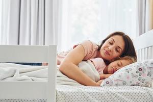 hora de dormir. joven madre con su pequeña hija vestida de forma informal juntas en casa foto