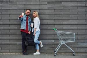 con carrito de compras. joven elegante con mujer en ropa casual al aire libre juntos. concepción de la amistad o las relaciones foto