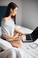 Using laptop. Young woman resting and spending weekend at home alone at home photo