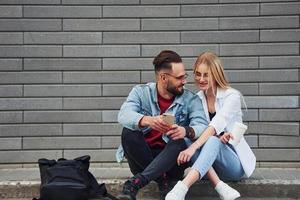 joven elegante con mujer en ropa casual sentados juntos al aire libre. concepción de la amistad o las relaciones foto