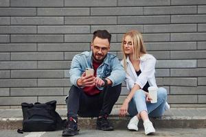 joven elegante con mujer en ropa casual sentados juntos al aire libre. concepción de la amistad o las relaciones foto