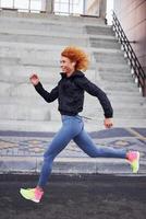 Young european redhead woman in sportive clothes running outdoors photo