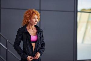 Young european redhead woman in sportive clothes standing outdoors photo