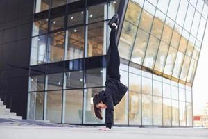 Doing crazy tricks. Young brunette in sportive clothes have fitness day outdoors in the city photo