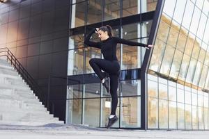 joven morena con ropa deportiva tiene un día de fitness al aire libre en la ciudad foto