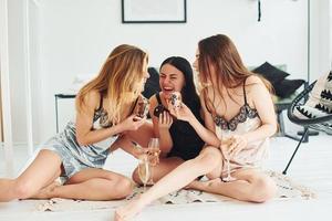 Cheerful young women in pajamas sitting on the floor indoors at daytime together photo