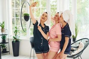 Cheerful young women in pajamas having fun indoors at daytime together photo