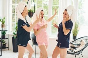 alegres mujeres jóvenes en pijama divirtiéndose juntas en el interior durante el día foto