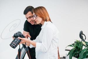 hombre vestido de negro viendo fotos en la cámara del fotógrafo femenino