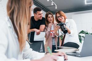 Group of business people in formal clothes indoors in the office looking at photos on the camera