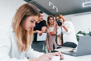 mujer haciendo fotos con cámara. grupo de empresarios vestidos de forma formal en el interior de la oficina