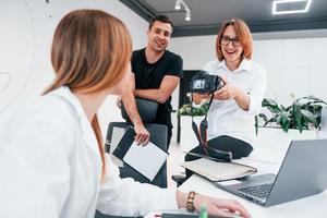 Group of business people in formal clothes indoors in the office looking at photos on the camera