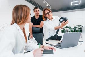 Group of business people in formal clothes indoors in the office looking at photos on the camera