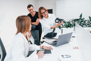 Group of business people in formal clothes indoors in the office looking at photos on the camera