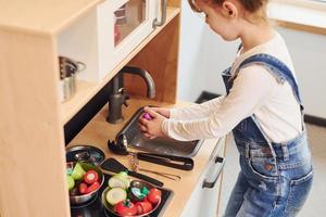 Little girl in casual clothes have fun by playing with toys on the kitchen photo