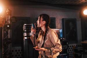 Young beautiful female singer rehearsing in a recording studio photo
