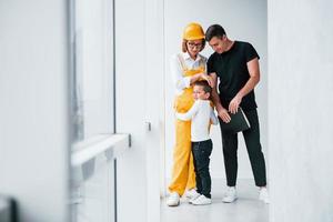 trabajadora en uniforme amarillo de pie en el interior con el hombre y el niño foto