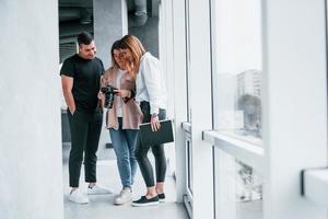 grupo de personas de pie juntas en el interior y miran fotos en la cámara