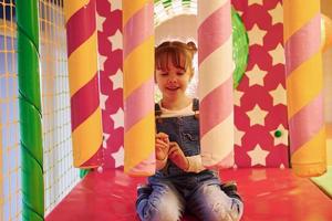 Happy little girl in casual clothes have fun in children's game complex photo