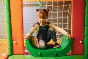 niña feliz con ropa informal se divierte en el complejo de juegos para niños foto