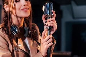 Young beautiful female singer rehearsing in a recording studio photo