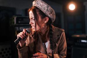 Young beautiful female singer rehearsing in a recording studio photo