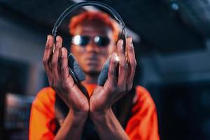 Young african american performer standing in a recording studio and holding headphones photo